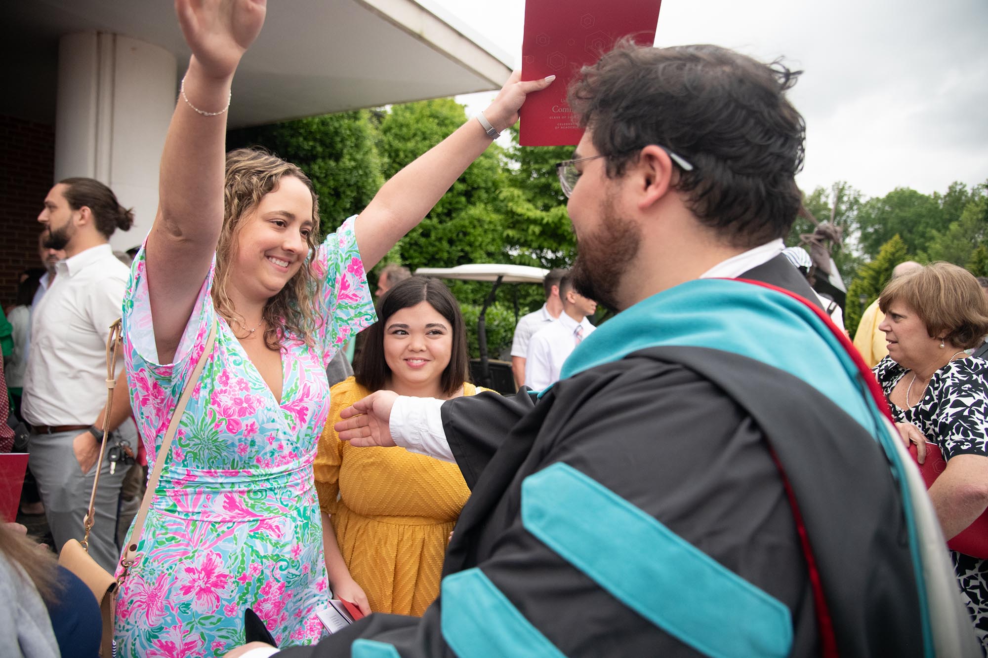 Man in doctorate regalia greets family.