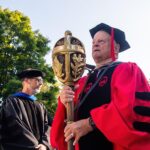 Frank Whitehouse, professor of marketing and chair of the marketing department, carries the University of Lynchburg Mace at the head of the 2024 Convocation procession. This official symbol of academic authority is carried by the University marshal, the senior faculty member, at Convocation and all official ceremonies. The Mace was carved from a pine ceiling beam from Westover Hall, the University’s original building, which was dismantled in 1970.