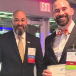 Brian Britt poses smiling and holding certificate with a colleague after winning the emerging leader award from APTA Virginia.