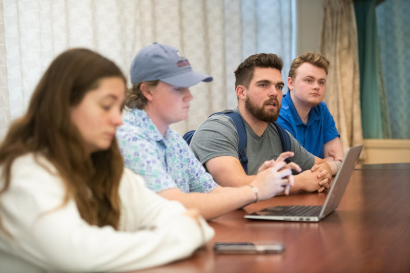 Group of female and male students sitting at a table with laptops