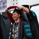 A Doctor of Physical Therapy graduate is hooded by faculty during commencement.